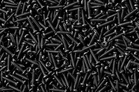 Abstract background pile of shiny black screws