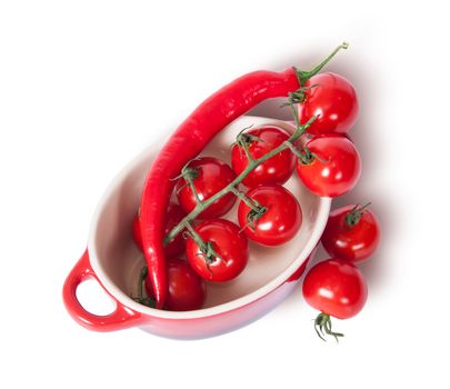 Cherry tomatoes and chili peppers in the saucepan top view isolated on white background