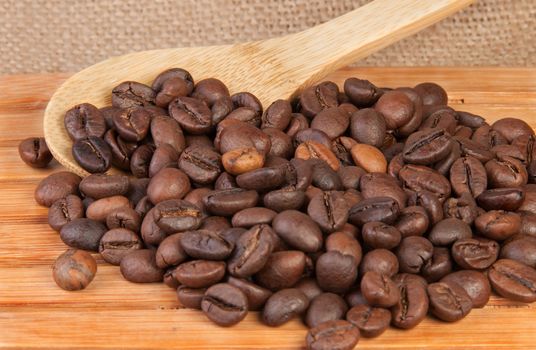 Coffee beans on a wooden lattice with a wooden spoon on burlap background