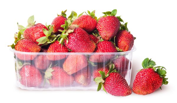 Freshly strawberries in a plastic tray and two near isolated on white background