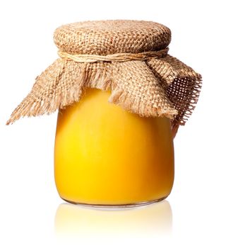 Honey in a glass jar covered with burlap isolated on white background