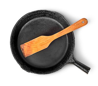Old cast iron pan with wooden spatula top view isolated on white background