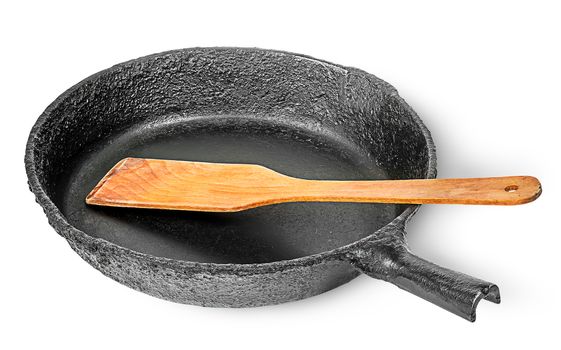 Old cast iron pan with wooden spatula isolated on white background