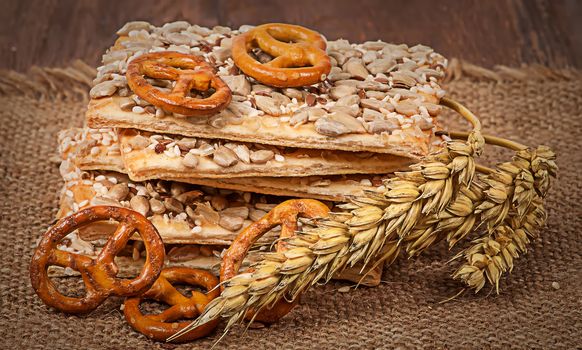 Pile cereal cookies with seeds and wheat ears on sacking and wooden table