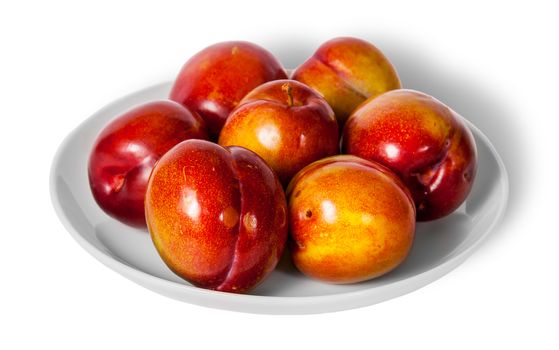 Red and yellow plums on white plate isolated on white background