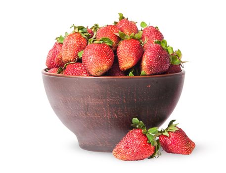 Ripe juicy strawberries in a ceramic bowl and two near isolated on white background