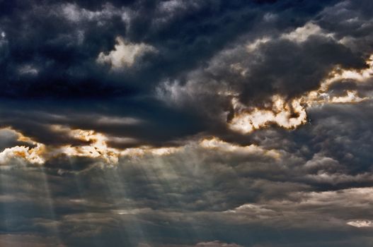 Dark stormy sky with a dramatic sunbeams