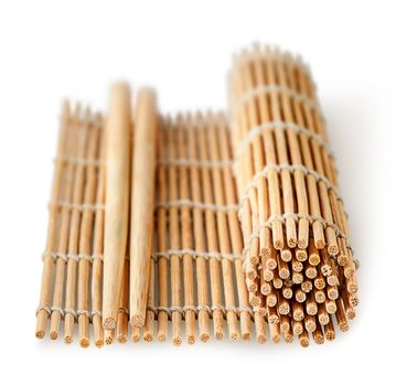 Sushi mat partially deployed and chopsticks perspective isolated on a white background