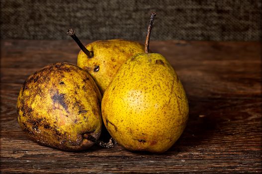 Three old pears on a wooden table background sacking