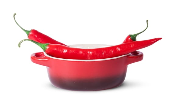 Three red chili peppers in saucepan isolated on white background