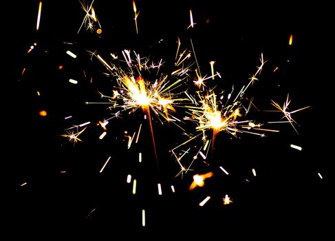 Two bright festive New Year Christmas sparklers on black background