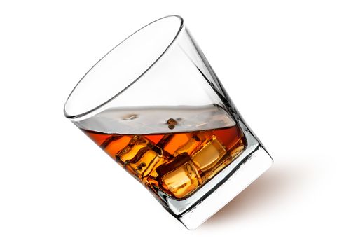 Whiskey with ice in a tilted glass isolated on white background