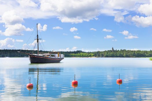 A buoy, clouds and a yacht on the lake on sunny, calm summer day