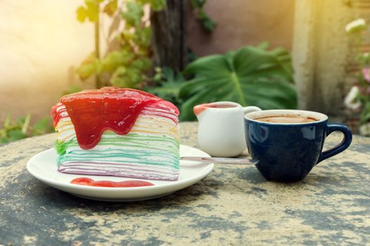 crepe cake rainbow and hot espresso coffee in garden side home. crape cake with strawberry sauce