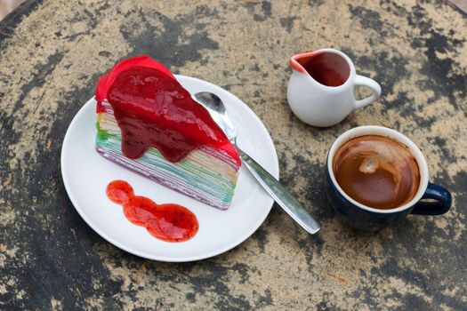 crepe cake rainbow and hot espresso coffee in garden side home. crape cake with strawberry sauce