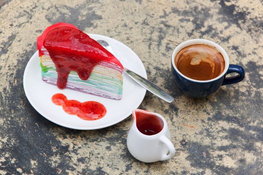 crepe cake rainbow and hot espresso coffee in garden side home. crape cake with strawberry sauce