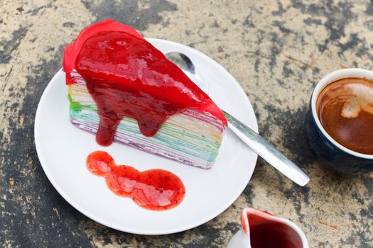 crepe cake rainbow and hot espresso coffee in garden side home. crape cake with strawberry sauce