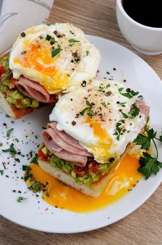 poached  eggs with avocado, tomatoes, slices of ham on a baguette for breakfast