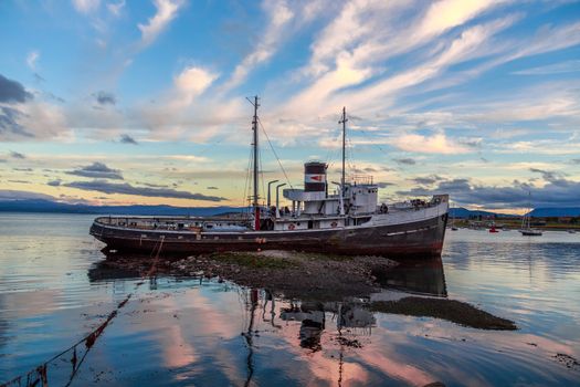 Old broken steamboat  stranded ashore in a sunset light, Ushuaia, Patagonia, Argentina