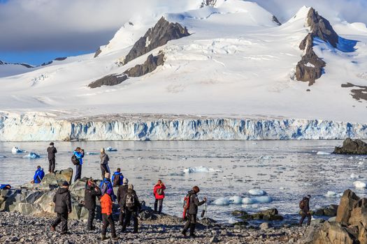 Group of tourists looking at the glacier at the stony shore of Half Moon Island, Antarctic