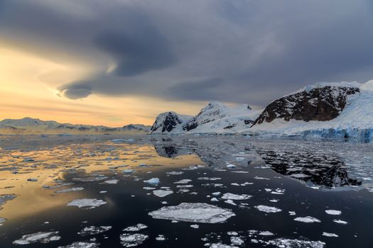 Sunset over the mountains and drifting icebergs at Lemaire Strait, Antarctica