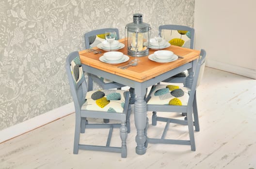 Dining table with chairs, plates, bowls and cutlery. Shabby chic dining room interior.