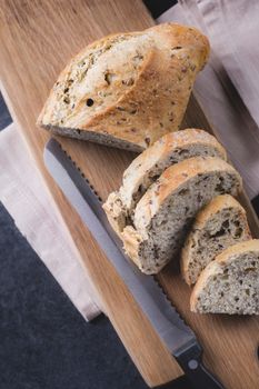 Sliced loaf of bread and a knife on a wooden cutting board