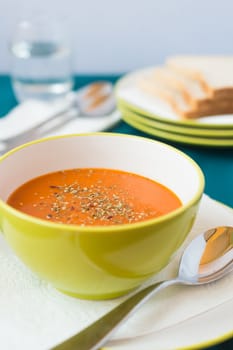tomato soup in a bowl with toast in a background
