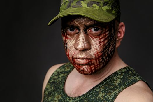 Portrait of Soldier with Military Style Camouflage on a  Face.  Portrait  on black background