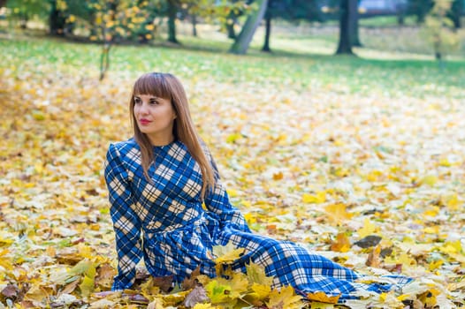 beautiful, dreamy girl with long straight hair in a blue long dress in the park in autumn