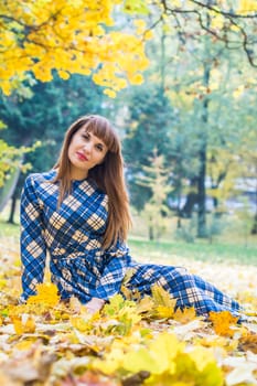 beautiful, dreamy girl with long straight hair in a blue long dress in the park in autumn