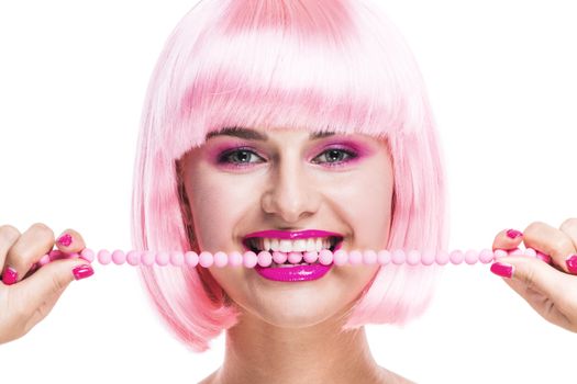 Portrait of girl with glamour make-up and pink hair biting beads isolated on white background