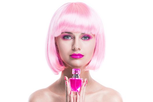 Portrait of girl with glamour make-up and pink hair holding perfume bottle isolated on white background