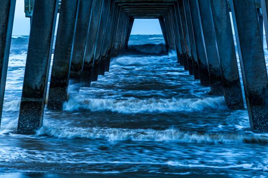 A stormy morning crashes ocean waves against the pier at Tybee Island, Georgia.