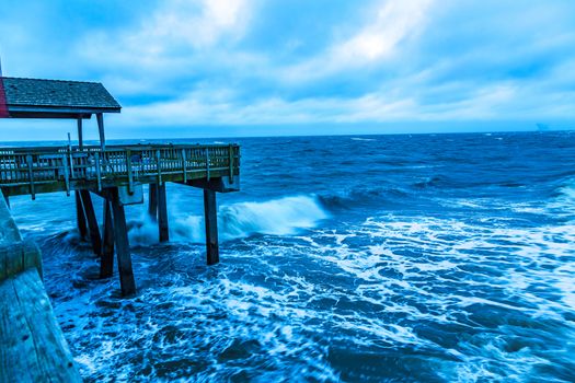 A stormy morning crashes ocean waves against the pier at Tybee Island, Georgia.