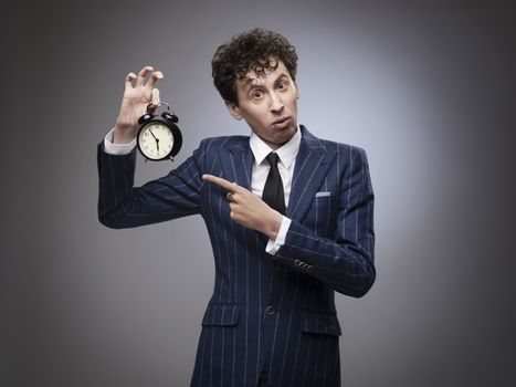 Funny businessman pointing to alarm clock showing time of deadline