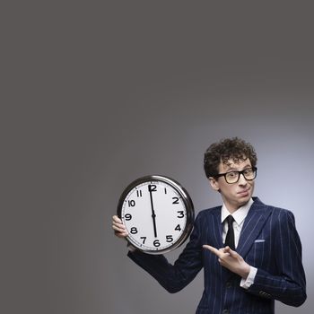 Funny businessman pointing to big wall clock showing time of deadline