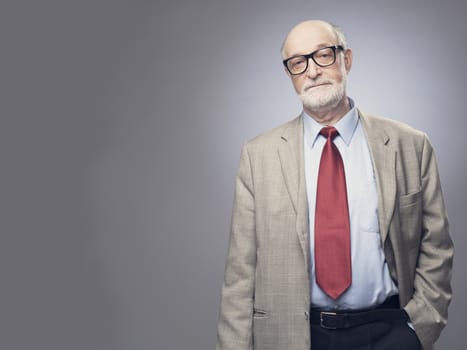 Portrait of handsome senior man in suit on gray background with copy space