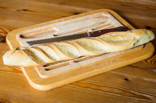 Close up french bread baguette on vintage wooden board with knife
