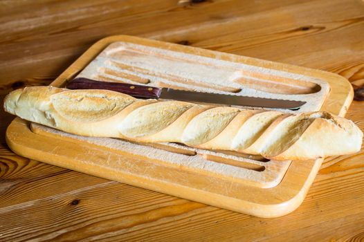 Close up french bread baguette on vintage wooden board with knife