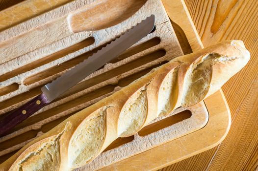 Close up french bread baguette on vintage wooden board with knife