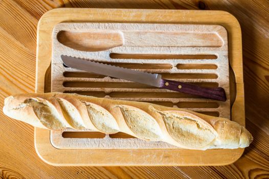 Close up french bread baguette on vintage wooden board with knife