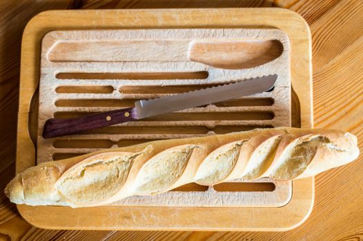 Close up french bread baguette on vintage wooden board with knife