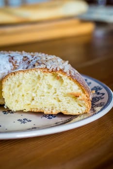 Close up brioche bread in a white plate on a wooden table. Baguette like fuzzy background