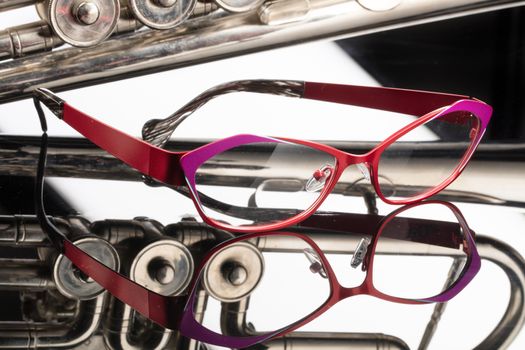 Fashinable glasses and trumpet on a studio galss background