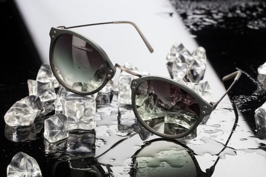 Sunglasses and crystals of ice on a studio glass background