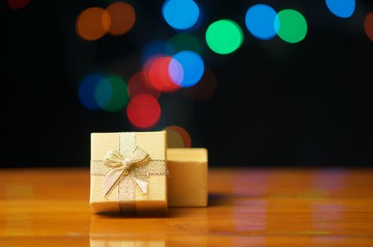 Gold present box open lid on wood table have colorful bokeh explode as background.