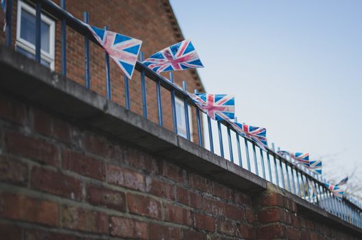 small union jack flags on a balcony in windy cold weather. typical british red brick building in the background
