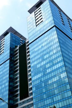 Closeup of modern skyscraper near palm against blue sky