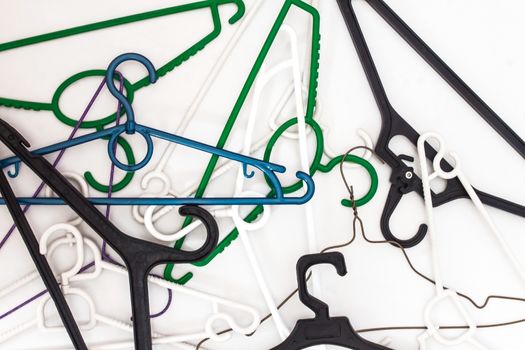 Many hangers of different shapes and colors, top view, white background.